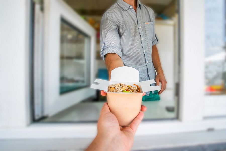 Atendente entregando o pedido pela janela do food truck