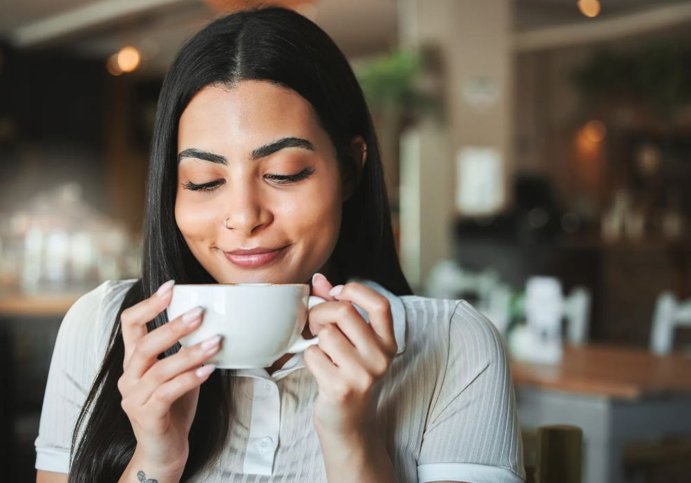 Cliente sentindo o aroma do café na mesa