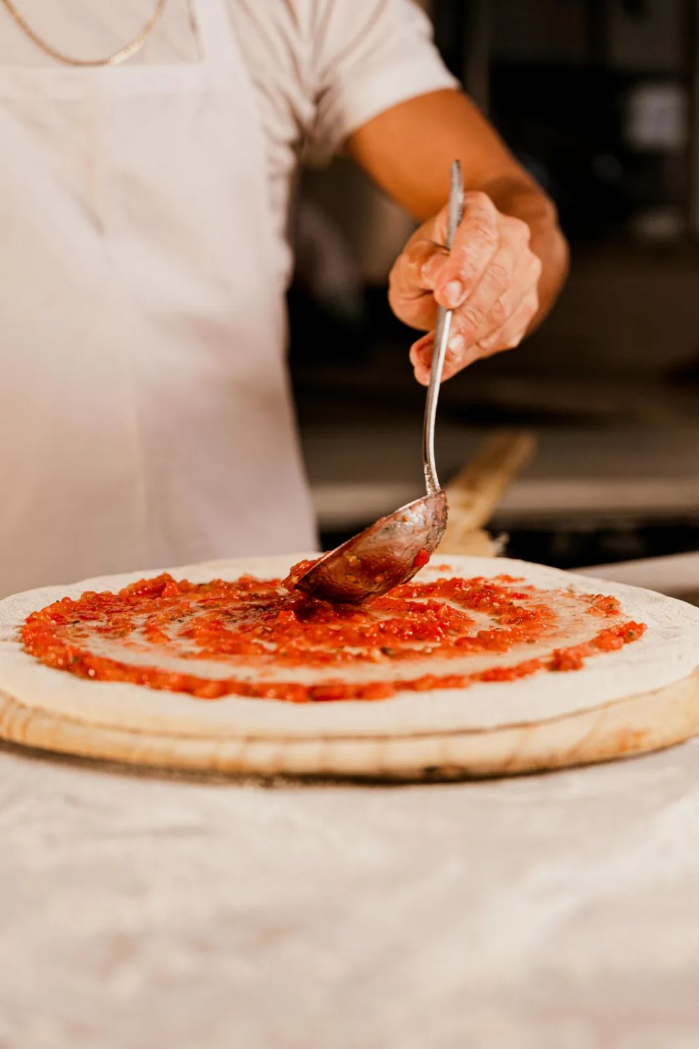 Pizzaiolo espalhando o molho na massa